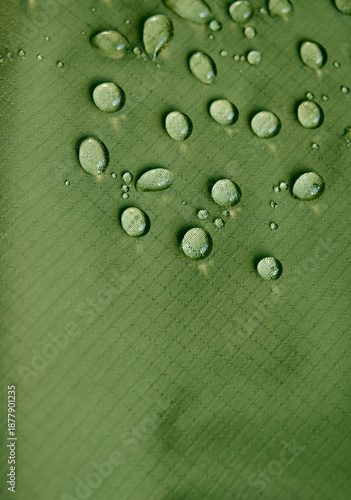 Water drops on waterproof membrane fabric. Detail view of texture of green waterproof cloth.