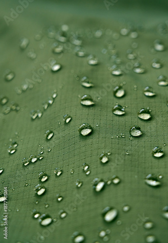 Water drops on waterproof membrane fabric. Detail view of texture of green waterproof cloth.