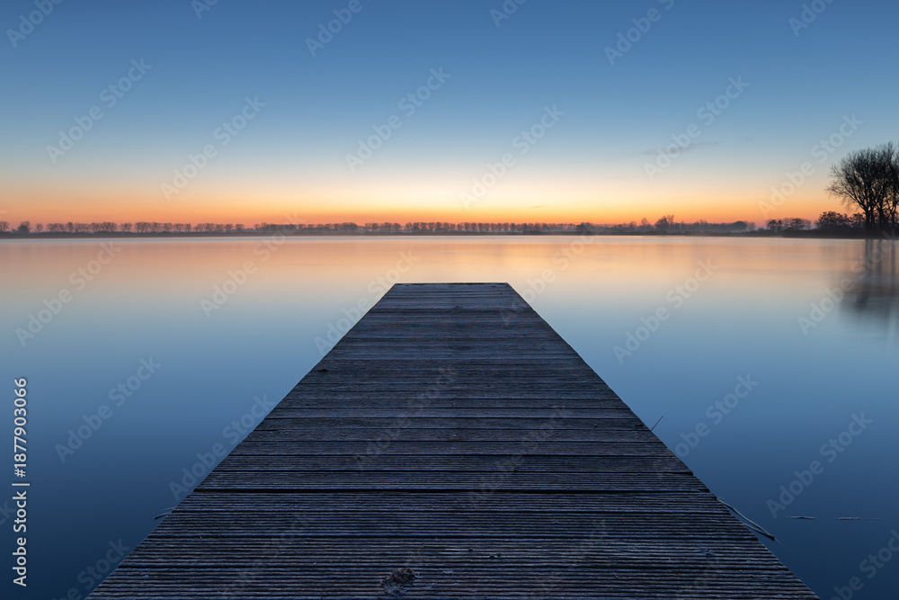 Fototapeta premium A pier on the lake in Dirkshorn during the blue hour. A moment of peace and serenity, to be fully present in the here and now.