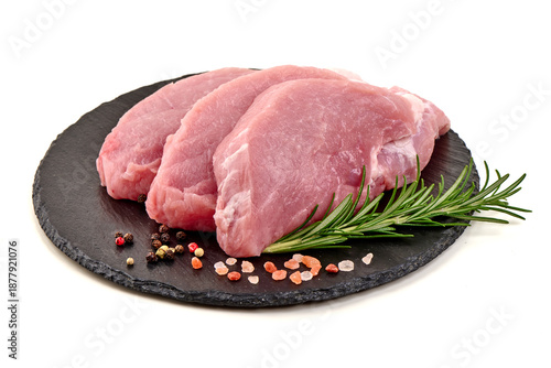 Raw pork steaks on slate plate, isolated on white background