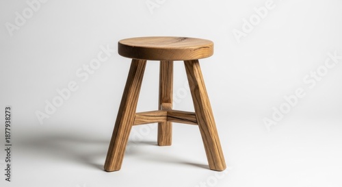 Simple, rustic wooden stool with three legs, isolated against white backdrop