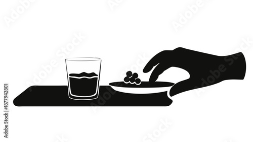A silhouette of a hand picking up a date from a plate next to a glass of water on a minimalist table.
