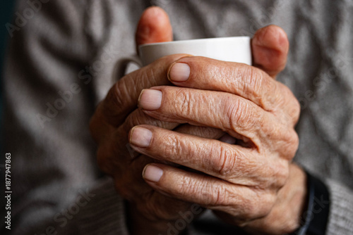 Senior hands holding hot coffee cup at home