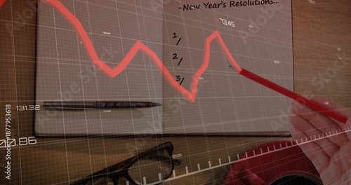 Sketching right-hand in red sleeve using red pencil on open notebook on desk with data overlay