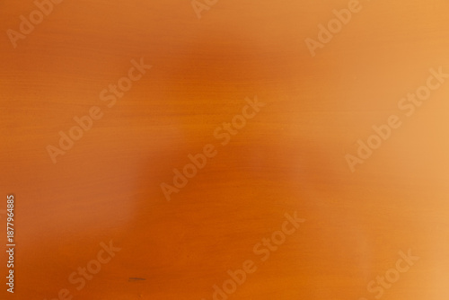 Superficie de madera pulida con veta sutil y tono cálido.Primer plano de superficie de madera lisa color naranja-marrón con veta horizontal, sombra tenue y marca oscura.