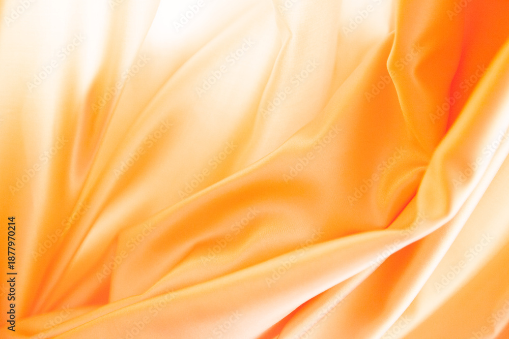 Obraz premium Primer plano de tela de satén naranja con pliegues suaves, reflejos brillantes y textura fluida.sensualidad y movimiento, simbolizando elegancia, suavidad y expresividad textil.