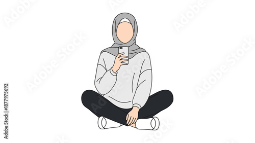 Young woman wearing a hijab sits cross legged holding a mobile phone connected to the internet for communication and information access