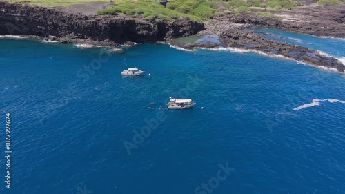 Aerial drone footage featuring a smooth orbit shot approaching a diving boat with divers visible on board, then pulling back to an overhead view near the coast in Cap La Houssaye Reunion Island.