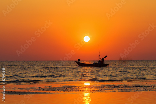 The sun begins to set and the silhouette of a fishing boat.