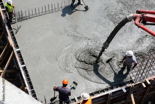 Construction workers pouring concrete on a building site using a pump hose