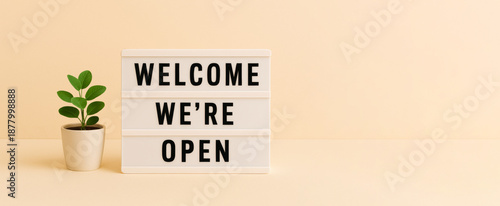 Lightbox with welcome were open message and small potted plant, background
