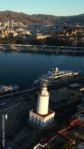 Malaga Spain aerial view featuring la farola lighthouse port yachts cityscape and mountains during early morning golden hour