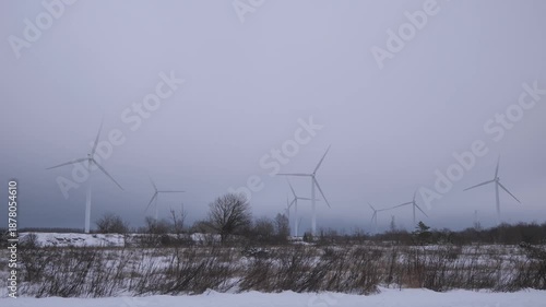 Wind turbines turn in snowy landscape on a cloudy winter day