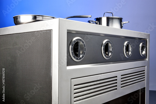 Modern stove with frying pan and pot, numbered knobs and vent panel. Clean studio setup with blue gradient background.