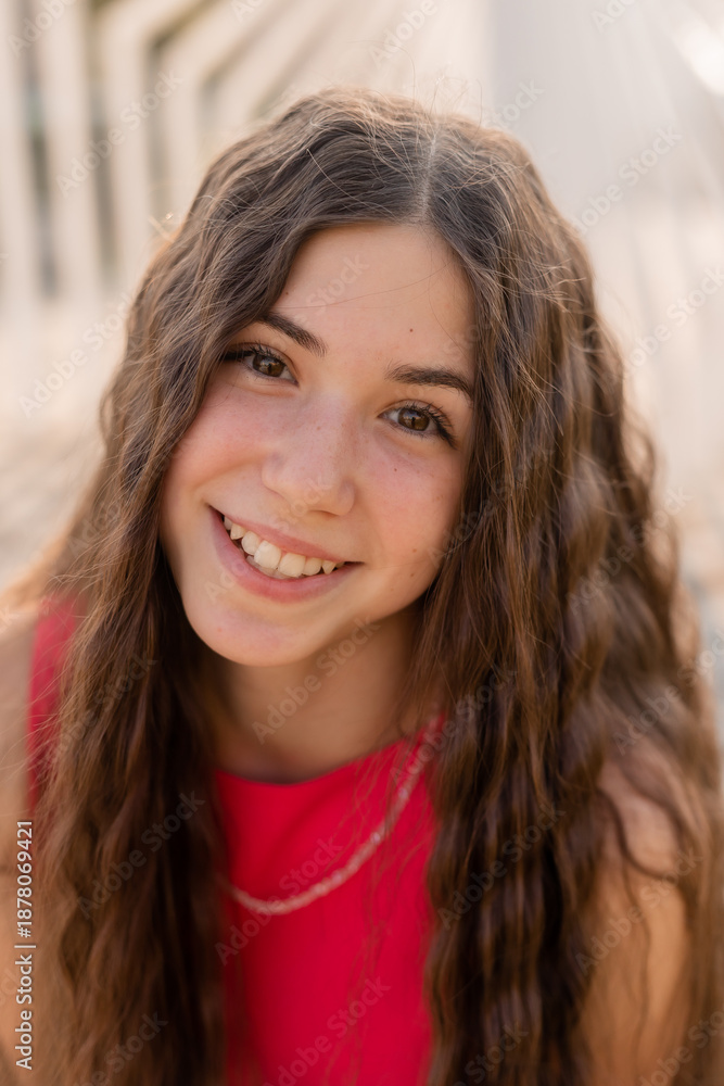 Obraz premium beautiful teenage brunette girl with long hair, smiling, looking at the camera during a summer walk