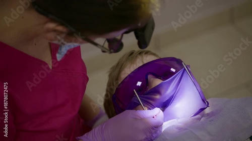 Close up view of a child undergoing dental care in slow motion, highlighting the gentle approach of the dentist and the use of protective eyewear during the procedure.