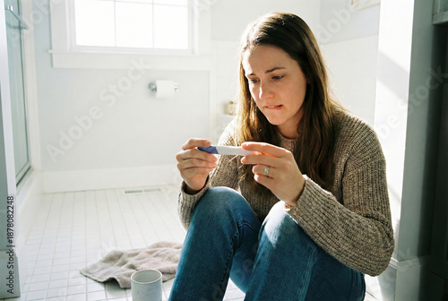 Young woman reacting to pregnancy test results in a bright bathroom