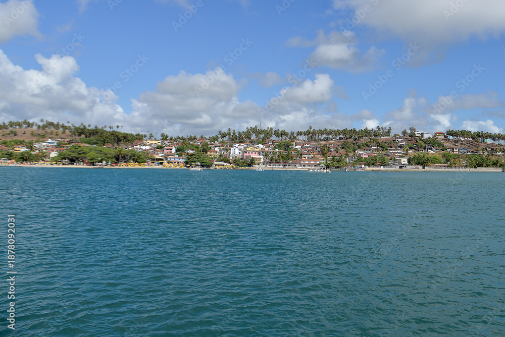 Fototapeta premium panoramic view of barra do cunhaú village from the river, scenic coastal town landscape in rio grande do norte brazil, tropical riverside village with coconut trees and blue water, summer travel desti