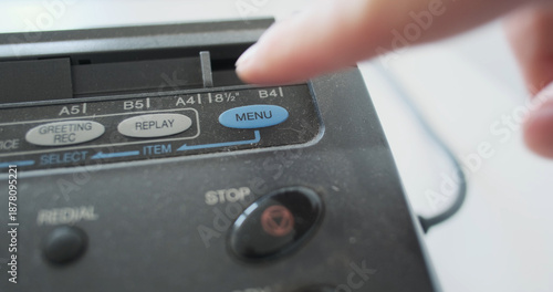 finger pressing menu button on an old fax machine, close-up, analog transmission of information. Concept settings of old digital devices, mechanical buttons