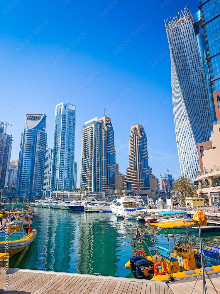 Fototapeta premium 01 08 2026 - Dubai, United Arab Emirates. Dubai Marina pier with many luxury yachts, capturing modern waterfront and city skyline with skyscrapers. Floating boats on canal