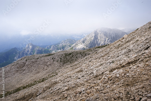 Stunning, misty view of Triglav mountain range with sharp mountain ridges under a cloudy sky