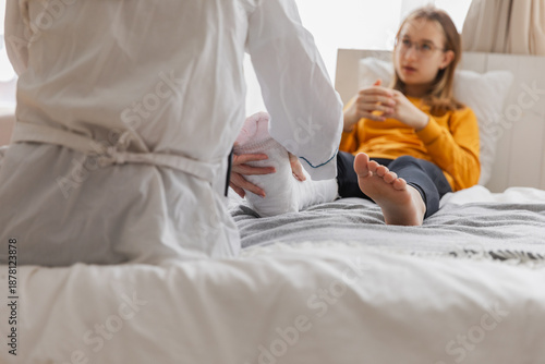 Girl with broken leg and doctor in clinic. Traumatologist orthopedist examines child leg in medical office. Doctor examining girl with medical plaster leg cast after broken ankle injury Rehabilitation