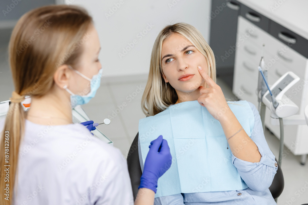 Fototapeta premium Dentist holding dental mirror and listening to patient describing toothache