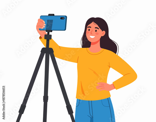 A confident young woman films herself with a smartphone on a tripod, creating content for a vlog or social media channel against a plain background.
