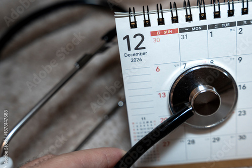 Close-up of a calendar page open to December 12, 2026, with a stethoscope attached, symbolizing healthcare and appointments, emphasizing planning and time management in medical settings.