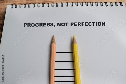 Concept of progress not perfection write on book isolated on Wooden Table.