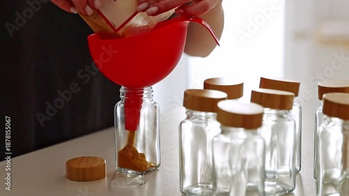 A girl pours spice seasoning from a bag into a jar.