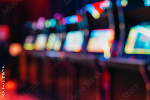 Blurred row of vintage arcade machines with colorful illuminated screens, background