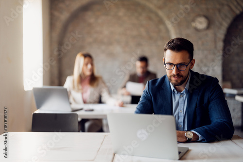 Fotografi Three focused business professionals working at their separate desks in a modern open-plan office