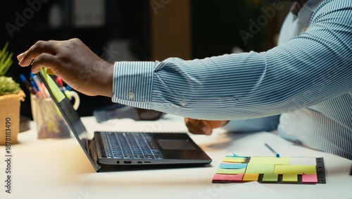 Billede på lærred African american person writing a yellow memo sticker as a reminder, trying to finish a task at the office after hours