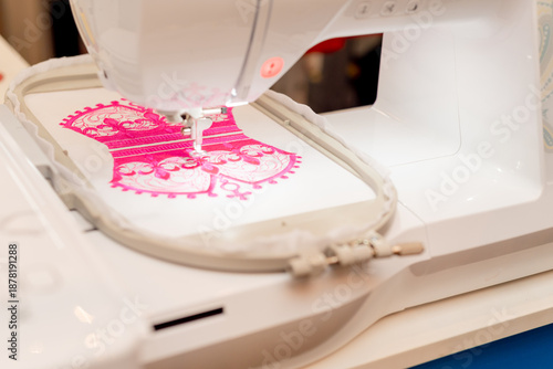 Close-up of a person using a modern computerized sewing machine, selecting decorative stitches. Detailed view of the needle and presser foot sewing on white fabric