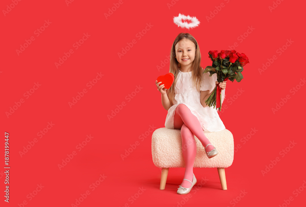 Fototapeta premium Cute little girl dressed as cupid with bouquet of beautiful rose flowers and gift box sitting on pouf against red background. Valentine's Day celebration