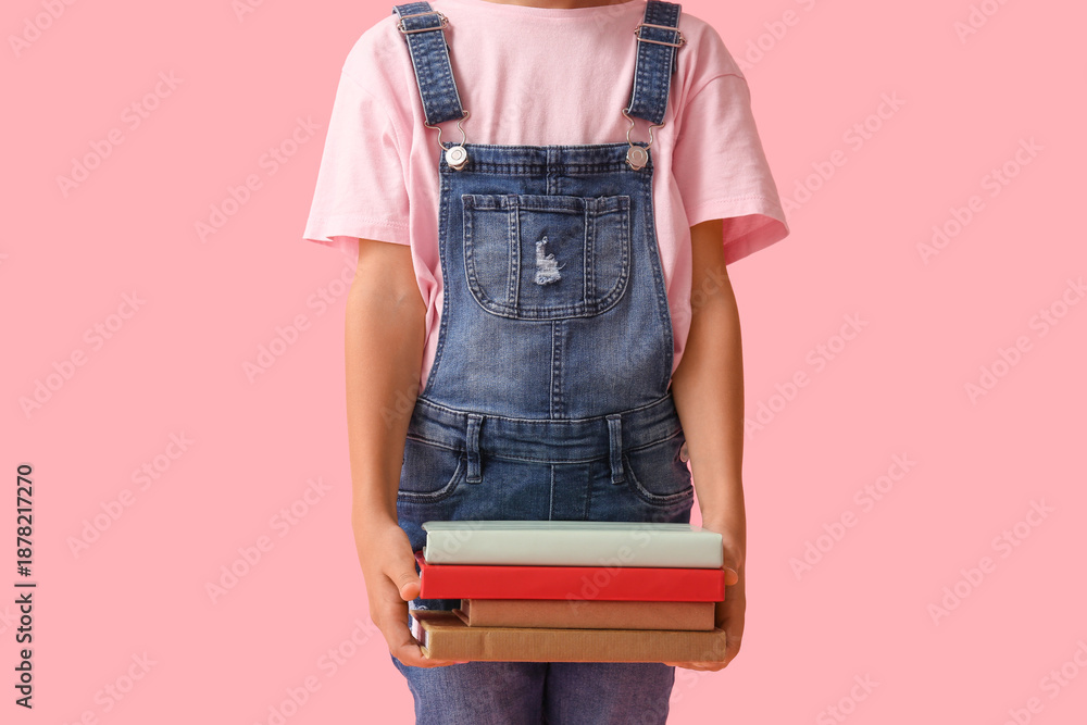 Naklejka premium Little girl with stack of books on pink background