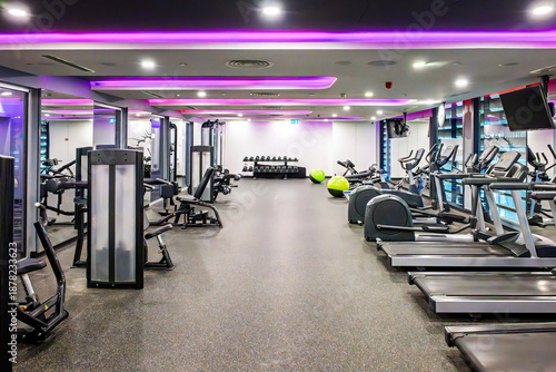 The interior of a well equipped gym and exercise facility featuring cardio machines, treadmills, elliptical, strength machines and free weights.
