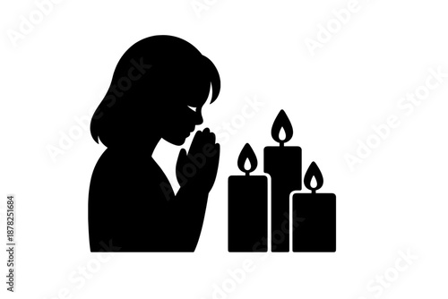 Silhouette of a person praying or mourning next to three burning candles
