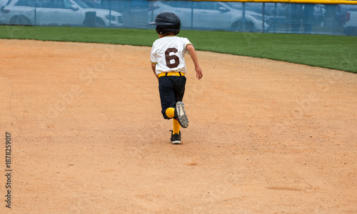 A youth baseball player running to base. A 6 year old boy playing baseball.