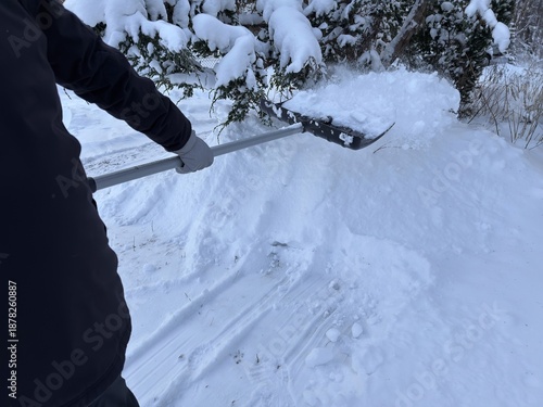 Man shoveling snow from driveway during winter snowfall  