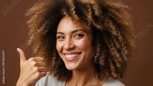 Happy Black Woman with Curly Hair Gives Thumbs Up, Smiling, Brown Background