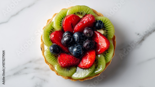 白大理石のテーブルの上に置かれたイチゴとキウイとブルーベリーを贅沢に盛り付けた色鮮やかなフルーツタルト