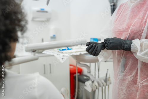 Female dentist putting on black nitrile gloves before starting a dental procedure