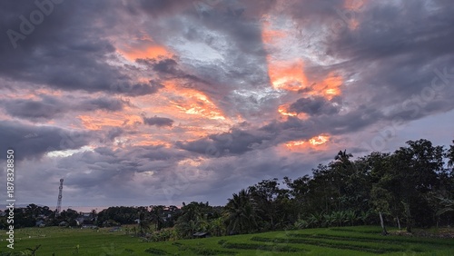 Vibrant sunset over lush green landscape with dramatic cloudy sky