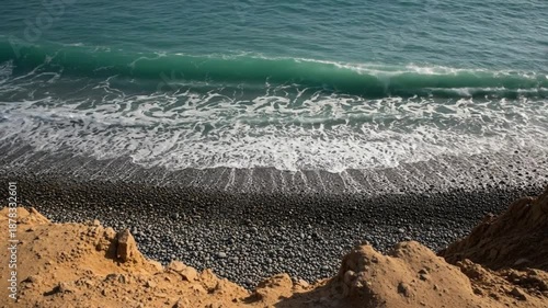 Ocean waves crashing on a rocky pebble beach shore, aerial view