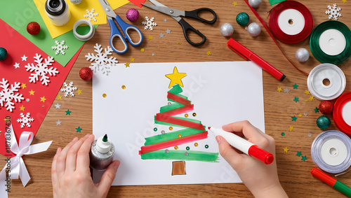 Top down view of child hands making Christmas card with glitter and markers