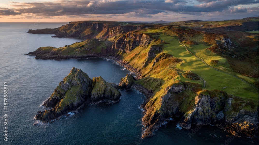 Obraz premium Coastal headland with steep cliffs, green slopes, and dramatic golden light