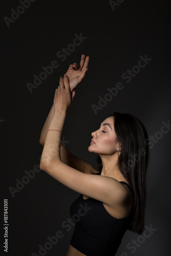 A woman with black hair wakes up in the morning in a white blanket and catches the rays of the sun. The portrait is creative, with brown eyes. High quality photo