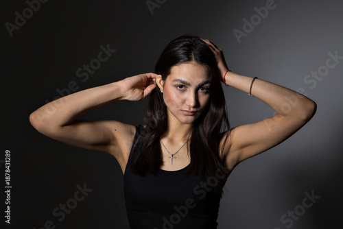 A woman with black hair wakes up in the morning in a white blanket and catches the rays of the sun. The portrait is creative, with brown eyes. High quality photo